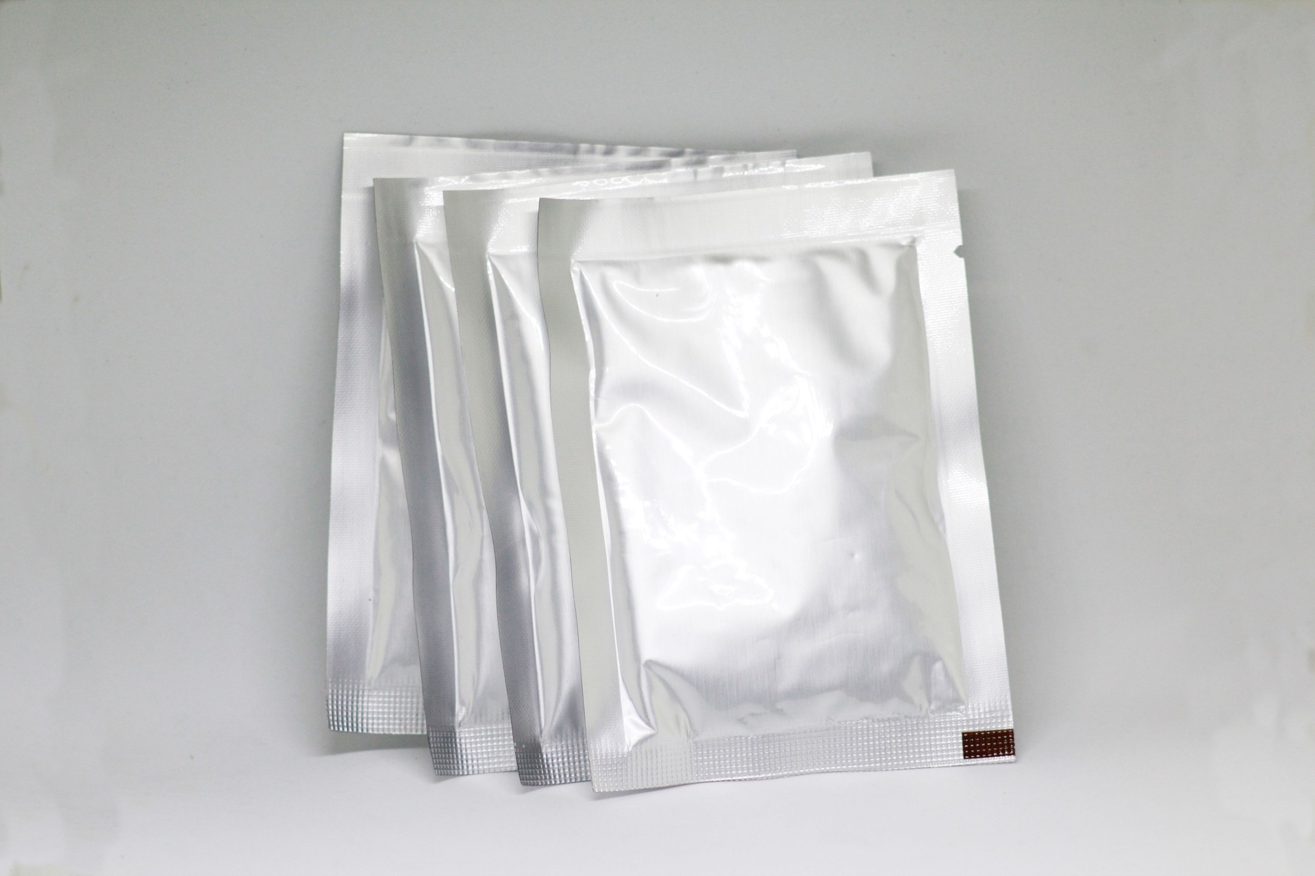 Close-Up Of Silver Packets On White Background